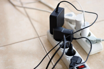 Overloaded power boards. Power strips with different electrical plugs on white floor. Concept of risk danger overloaded current electrical