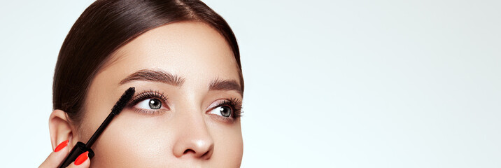 Beauty woman applying black mascara on eyelashes with makeup brush. Eyelash extensions. makeup,...