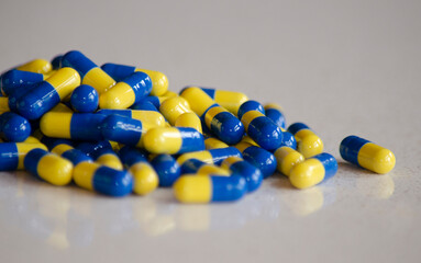 bottle with pills on marble table with blue and yellow pharmaceutical medicine capsules
