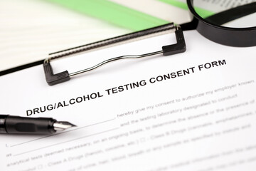 Drug and alcohol testing consent form on A4 tablet lies on office table with pen and magnifying glass close up