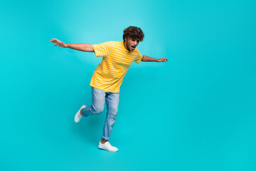 Fototapeta na wymiar Full length photo of nice young male fall try keep balance dressed stylish striped yellow garment isolated on cyan color background