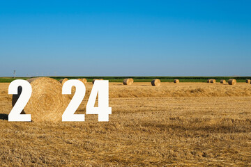 Happy New Year 2024 agricultural business concept. View of bales in the field.