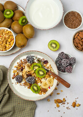 Bowl with yogurt and granola, fruits, nuts, flax seeds, berries. Healthy breakfast.