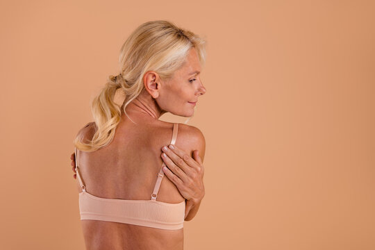Back rear spine view photo of body positive aged woman in top bra touch hug her self prepare for mamogram awareness isolated over pastel color background