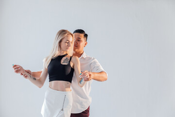 Man and woman dancers perform a dance on a white background in a studio