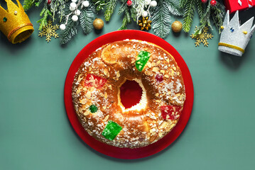 Top view of Roscon de reyes with cream and christmas ornaments on a red plate. Kings day concept...