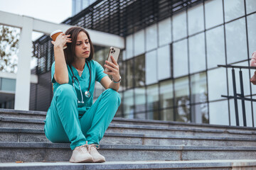 Upset female nurse. Medical professional looking unhappy. Shot of a young nurse looking stressed out while sitting at stairs in a hospital. Upset female nurse