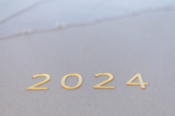 gold numbers 2024 on the sand by the sea