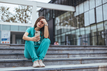 Fototapeta premium Upset female nurse. Medical professional looking unhappy. Shot of a young nurse looking stressed out while sitting at stairs in a hospital. Upset female nurse