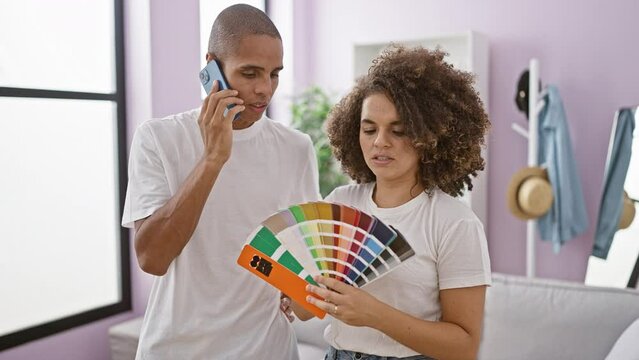 Lovely couple smiling, talking on smartphone, having fun choosing paint color for home interior