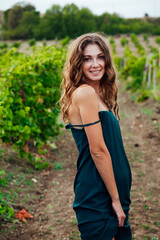 Beautiful brown-haired woman in a vineyard at sunset