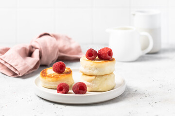 Cottage cheese fritters or syrniki served with raspberries.