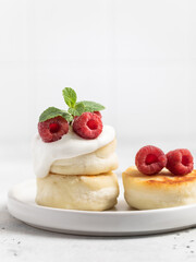Cottage cheese fritters or syrniki served with raspberries.