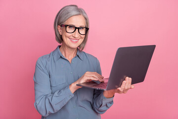 Photo of positive lovely pensioner office manager hr recruiter use modern wireless netbook isolated on pink color background