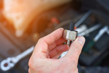 Repair man installing new knock sensor in car. Man repair broken car, engine detonation, change...