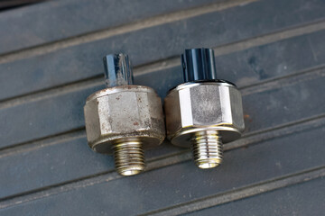 Replacing broken engine knock sensor, engine detonation. Knock sensor. Bad knock sensor and new one ready to replace. Faulty knock sensor, engine problems. Car maintenance. Selective focus