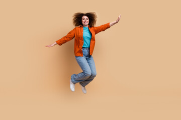 Fototapeta na wymiar Full length photo of positive lovely girl jumping up having fun rejoicing sale empty space isolated on beige color background
