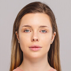 Naklejka premium Beautiful young girl looks at the camera after professional makeup. Model poses in front of the camera. An attractive girl with beautiful makeup. Close-up face of a white model with long hair.