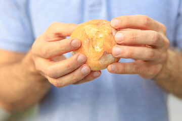 Guy's hand holds a round bun, snack and fast food concept. Selective focus on hands with blurred background