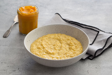Bowl of oatmeal with pumpkin on a gray textured background. Delicious healthy homemade breakfast