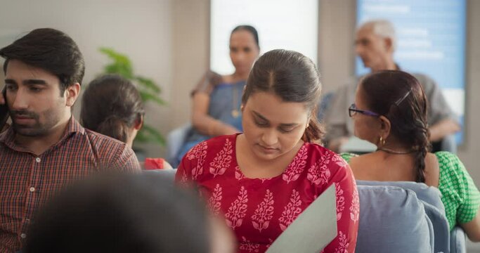Dolly Shot Showing Portraits of Patients Waiting in Reception Hall in a Hospital. Indian Diverse Group Talking, Checking Medical Analysis Report in a Busy Local Health Clinic During the Day