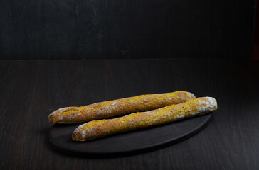 Thin homemade baguette on a black background