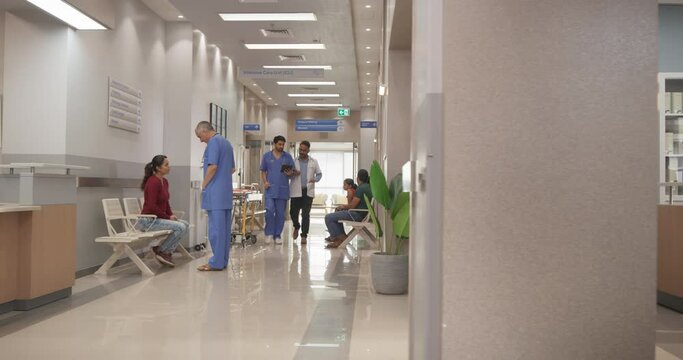 Tracking Dolly Shot of Hospital Corridor and Lobby Filled with Group of Diverse Indian Patients Waiting for their Appointments. Modern Health Clinic with Active Doctors, Nurses and Staff Working