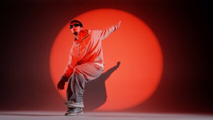 In the frame on a red background stands a young man on it shines a spotlight beam. Highlights him...