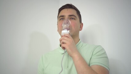 A young man breathes through an inhaler closeup. A man with an oxygen mask is being treated for a...