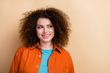Photo portrait of lovely young lady look interested empty space dressed stylish orange garment isolated on beige color background