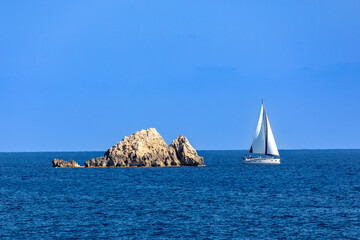 Segelboot bei einem Felsen im Meer bei Cala Rajada, Mallorca, Spanien