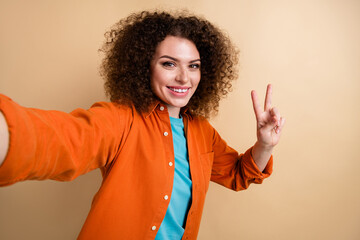 Photo of glad friendly lovely girl wearing stylish clothes recording video hand showing v-sign...