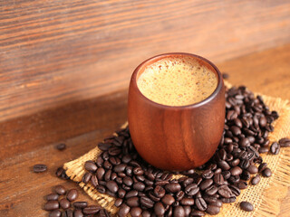 Hot coffee, cappuccino in a wooden cup and roasted coffee beans.