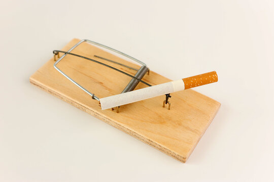 A man was tempted by a cigarette and fell into a trap of a mousetrap. Bad habit concept.