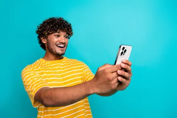 Gardinen Photo of handsome guy device instagram twitter facebook telegram dressed stylish striped yellow outfit isolated on cyan color background © deagreez