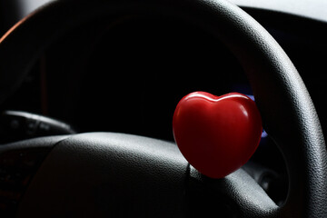 Corazón en el volante de un Automóvil. Concepto de salud y seguridad al volante.  - obrazy, fototapety, plakaty