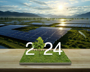 2024 white text with growing tree on green grass on open book on wooden table over solar photovoltaics farm located on mountain and sunrise, Happy new year 2024 green ecology and saving energy concept - obrazy, fototapety, plakaty