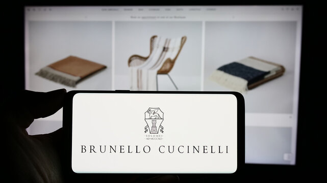 Stuttgart, Germany - 11-07-2023: Person holding mobile phone with logo of Italian fashion company Brunello Cucinelli SpA in front of business web page. Focus on phone display.