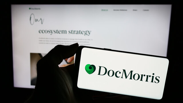 Stuttgart, Germany - 11-08-2023: Person holding smartphone with logo of Swiss online pharmacy company DocMorris AG in front of website. Focus on phone display.