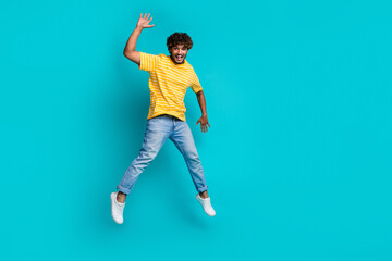 Full size photo of carefree overjoyed man jumping arm waving hi empty space isolated on teal color...