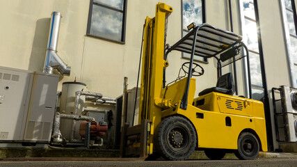 Yellow industrial forklift. There is no one there and the factory is empty.