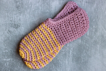 Handcrafted slippers made of organic yarn. Cute handmade footwear. Gray background with space for text. 
