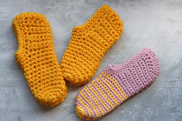 Handcrafted slippers made of organic yarn. Cute handmade footwear. Gray background with space for text. 