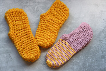 Handcrafted slippers made of organic yarn. Cute handmade footwear. Gray background with space for text. 