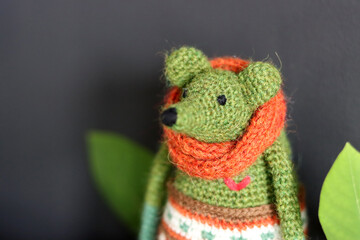 Crochet Amigurumi toy close up photo on dark grey background with copy space. Green mouse with orange scarf. Cute handmade gift. 