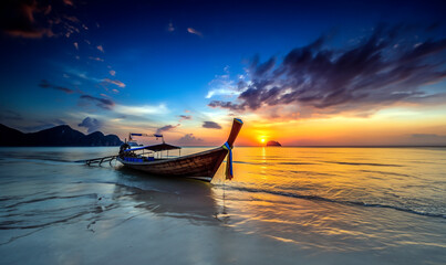 Inspiring travel photography, a sunset on the Thai coast, with a traditional fishing boat in the sand.