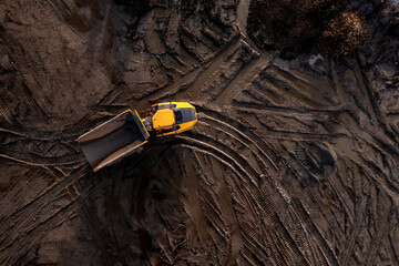Aerial view above an earth mover truck on a muddy construction site - obrazy, fototapety, plakaty