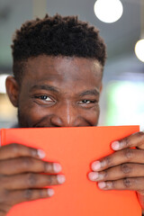 Young African American man with a happy expression, holding a book