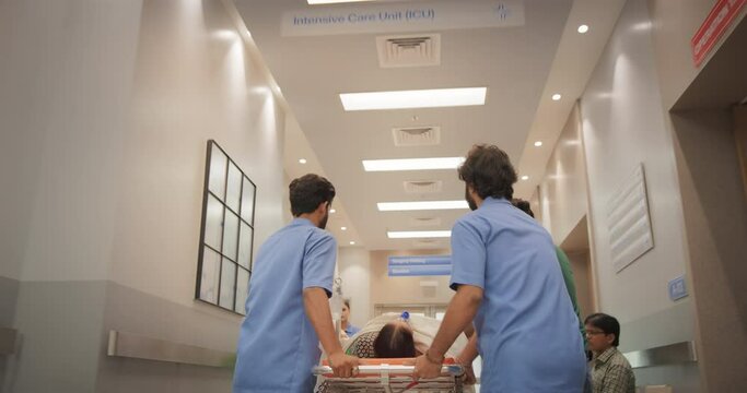 Backview Tracking Shot of Group of Medical Specialists Transporting an Elderly Patient with a Stretcher Through a Hospital Corridor. Health Clinic Receiving an Emergency Case for Intensive Care Unit