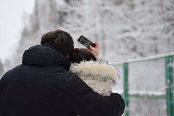 Młoda para robi selfie na tle śniegu - obrazy, fototapety, plakaty
